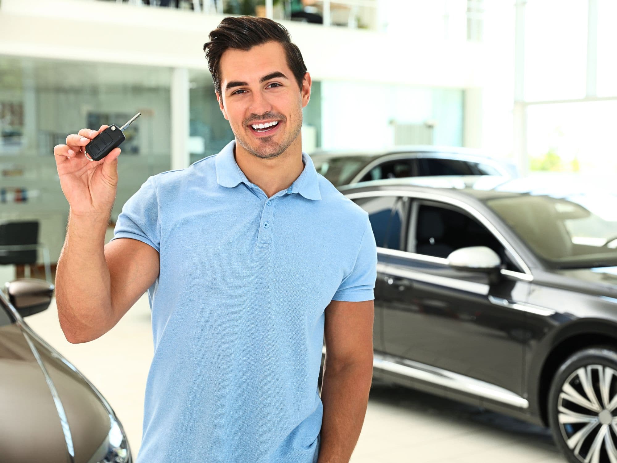 Homem segurando a chave do carro na concessionária
